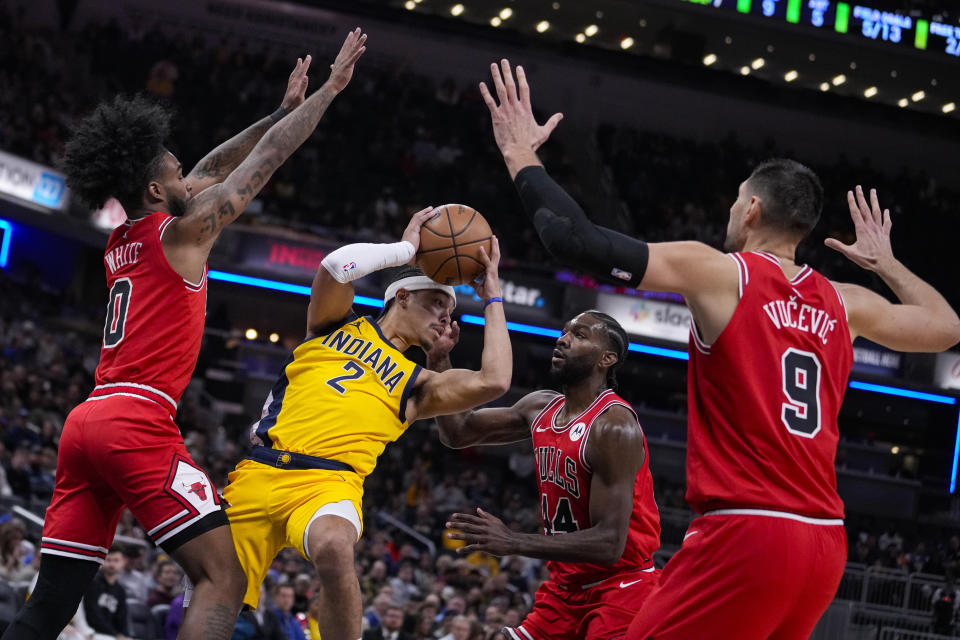 Indiana Pacers guard Andrew Nembhard (2) makes a pass surrounded by Chicago Bulls guard Coby White (0), forward Patrick Williams (44) and center Nikola Vucevic (9) during the first half of an NBA basketball game in Indianapolis, Monday, Oct. 30, 2023. (AP Photo/Michael Conroy)