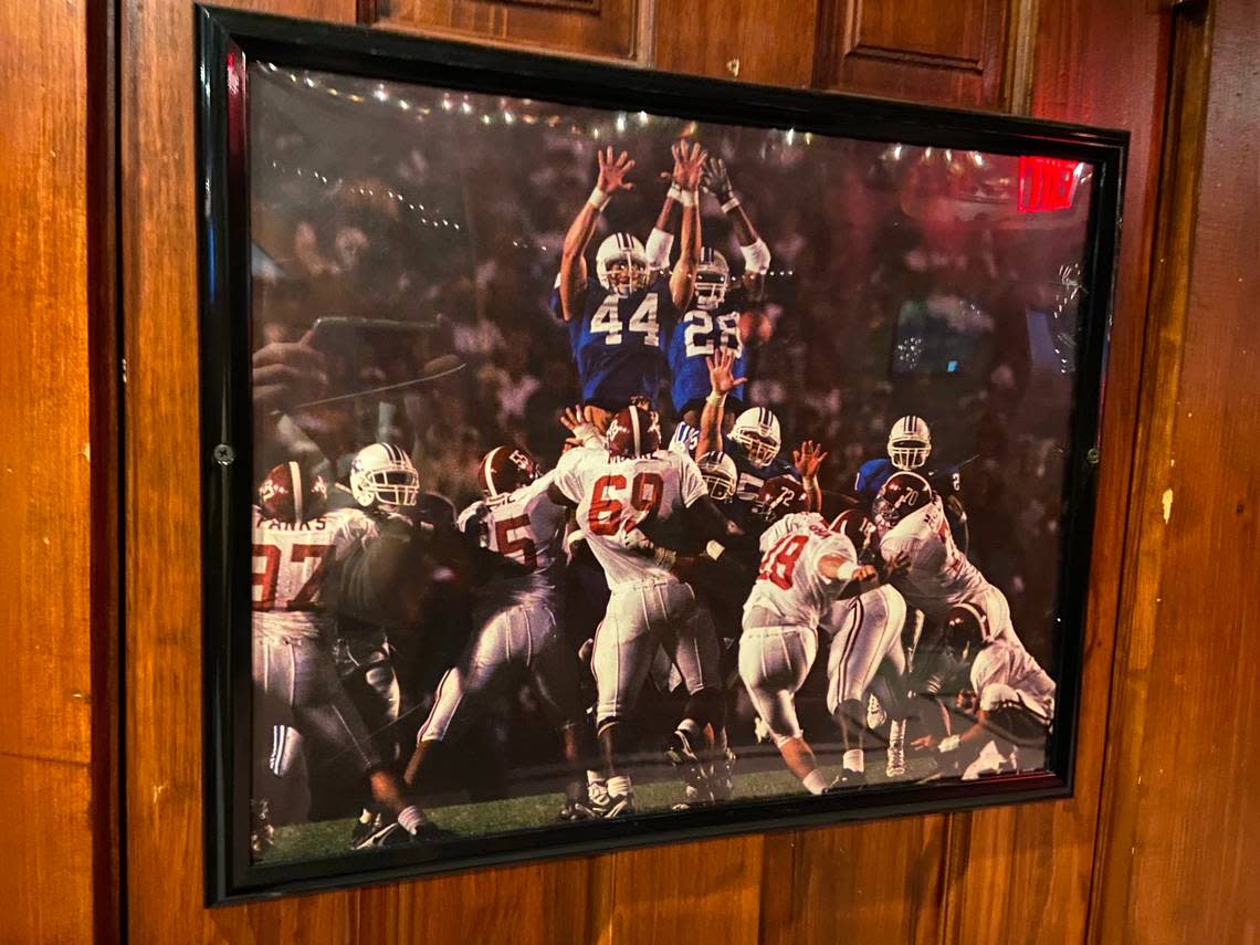 A framed photograph of former Kentucky football player David Ginn’s famed field goal block against Alabama in 1997 is shown inside Jack Demsey’s in New York City. All Kentucky football games are shown inside the multi-level bar and restaurant in Manhattan.