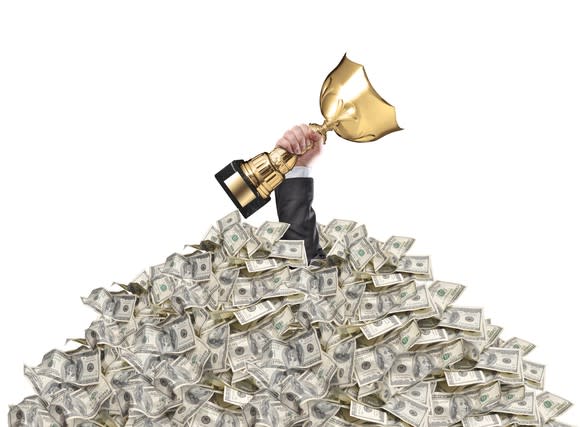 Hand clasping trophy sticking through a pile of cash