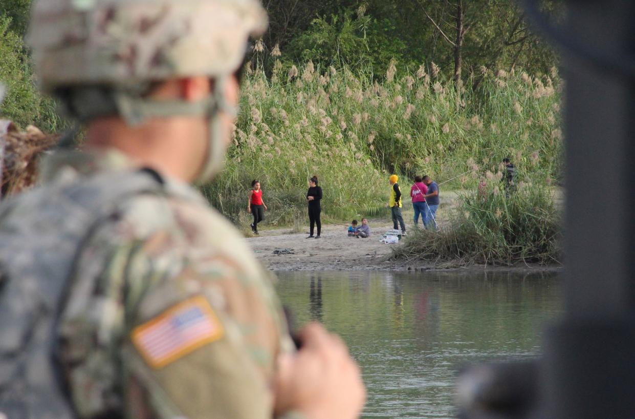 A soldier from Kentucky looks across the Rio Grande from Laredo, Texas, toward Nuevo Laredo, Mexico, at a group of people on the riverbank on Nov. 17, 2018. (Photo: Thomas Watkins/AFP/Getty Images)