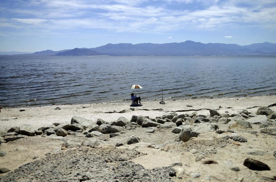 FILE - In this April 30, 2015 file photo, a man fishes for tilapia along the receding banks of the Salton Sea near Bombay Beach, Calif. California officials have proposed spending nearly $400 million over 10 years to slow the shrinkage of the state's largest lake. Gov. Jerry Brown's administration on Thursday, March 16, 2017, unveiled a plan to build ponds on the northern and southern ends of the Salton Sea. It's expected to evaporate at an accelerated pace starting next year when the San Diego region no longer diverts water to the desert region. (AP Photo/Gregory Bull, File)