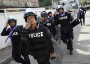 Thai riot police smile as they are cheered by anti-government protesters after demonstrations are called off outside Government House in Bangkok December 3, 2013. Thailand's government ordered police to stand down and allow protesters into state buildings on Tuesday, removing a flashpoint for clashes and effectively bringing an end to days of violence in Bangkok in which five people have died. REUTERS/Dylan Martinez