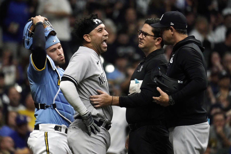 New York Yankees' Marwin Gonzalez, middle, reacts as he's checked on by a trainer after being hit by an errant throw from Milwaukee Brewers' Victor Caratini during the third inning of a baseball game Saturday, Sept. 17, 2022, in Milwaukee. Gonzalez exited the game. (AP Photo/Aaron Gash)