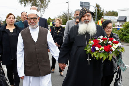 Imam Ibrahim Abdul Halim of the Linwood Mosque holds hands with Father Felimoun El-Baramoussy from the Dunedin Coptic Church, as they walk at the site of Friday's shooting outside the Mosque in Christchurch, New Zealand March 18, 2019. REUTERS/Edgar Su