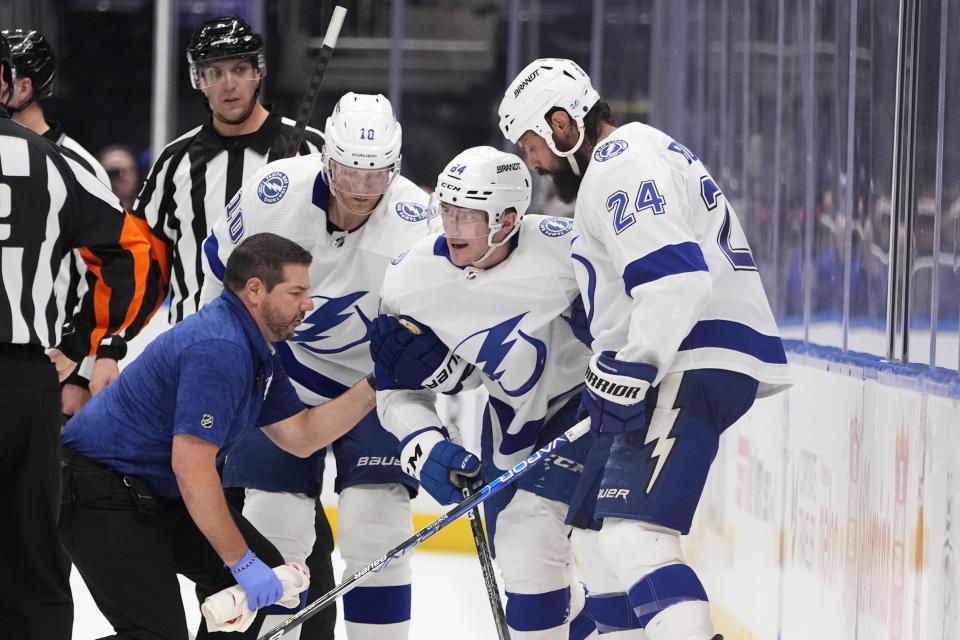 A Tampa Bay Lightning trainer and Corey Perry (10) and Zach Bogosian (24) help Tanner Jeannot (84) get up after Jeannot was hurt during the second period of the team's NHL hockey game against the New York Islanders on Thursday, April 6, 2023, in Elmont, N.Y. (AP Photo/Frank Franklin II)