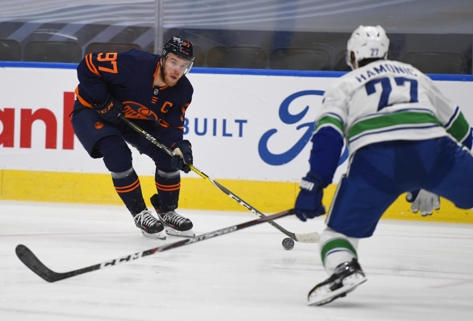 Edmonton Oilers' Connor McDavid (97) looks to get past Vancouver Canucks' Travis Hamonic (27) during the second period of an NHL hockey game Wednesday, Jan. 13, 2021, in Edmonton, Alberta. (Dale MacMillan/The Canadian Press via AP)