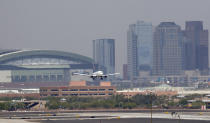 Heat waves ripple across the tarmac at Sky Harbor International Airport as downtown Phoenix stands in the background as an airplane lands, Tuesday, June 20, 2017 in Phoenix. The Phoenix City Council is mulling a vote to raise fees charged ride-hailing companies to $4 per trip to and from the airport. Council members Wednesday, Dec. 18, 2019 are to decide on the proposal to increase the current fee from $2.66 per pickup. (AP Photo/Matt York)