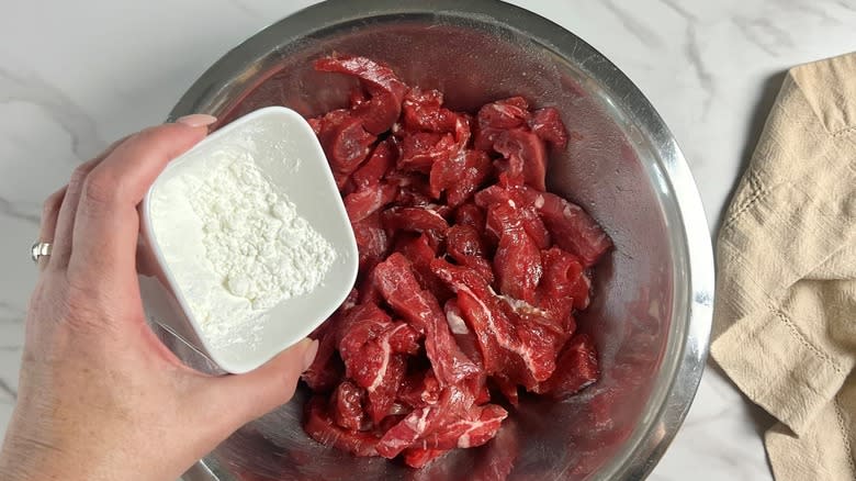 hand coating steak in cornstarch for velveting