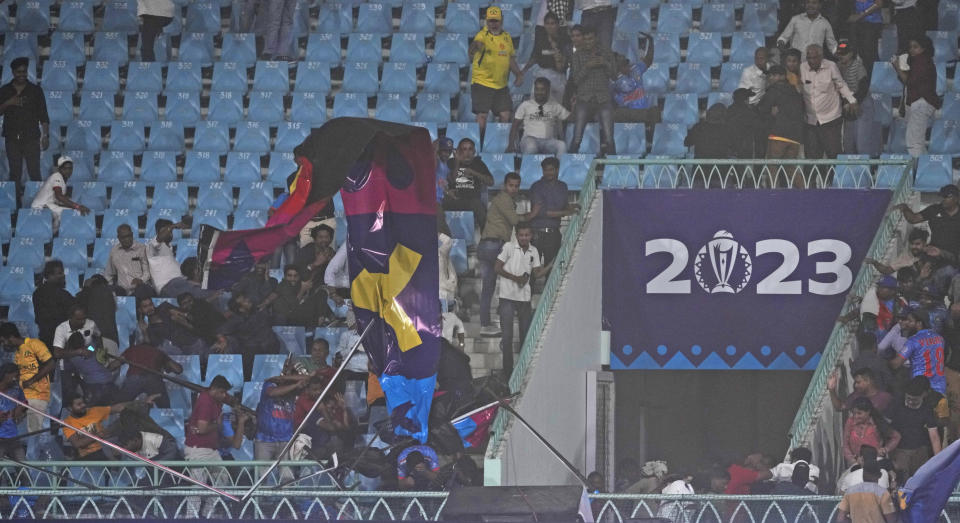 Spectators take cover and run after a banner fell due to strong winds accompanied by a storm during ICC Men's Cricket World Cup match between Australia and Sri Lanka in Lucknow, India, Monday, Oct. 16, 2023. (AP Photo/Rajesh Kumar Singh)