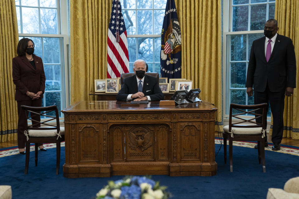 Vice President Kamala Harris, left, and Secretary of Defense Lloyd Austin, right, listen as President Joe Biden speaks before signing an Executive Order reversing the Trump era ban on transgender individuals serving in military, in the Oval Office of the White House, Monday, Jan. 25, 2021, in Washington. (AP Photo/Evan Vucci)