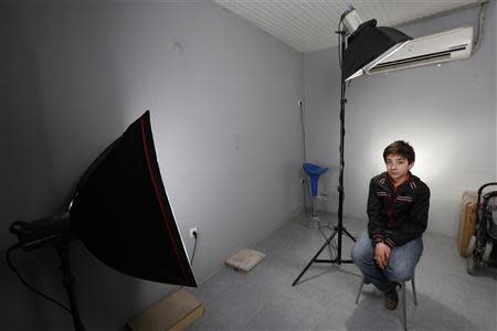 Hassan, a 13-year-old boy from southern Syrian town of Deraa, poses in the photography studio where he works in Kilis on the Turkish-Syrian border March 18, 2014. REUTERS/Murad Sezer