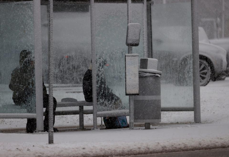 People wait at a bus stop on Orchard Lake Road in West Bloomfield on Friday, Jan. 12, 2024, during Metro Detroit's first winter storm of 2024