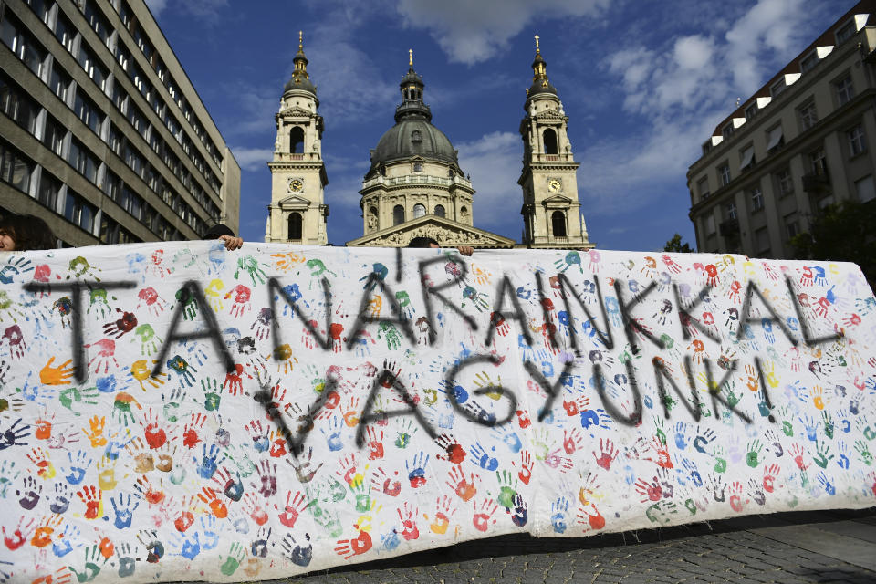 A banner reads "we stand by our teacher" during a students protest in solidarity with their teachers in front of the St. Stephen's Basilica in Budapest, Hungary, Friday, Sept. 2, 2022. Public schools in Poland and Hungary are facing a shortage of teachers at a time when both countries are taking in many Ukrainian refugee children. For years, teachers have been fleeing public schools over grievances regarding low wages and a sense of not being valued by their governments. (AP Photo/Anna Szilagyi)