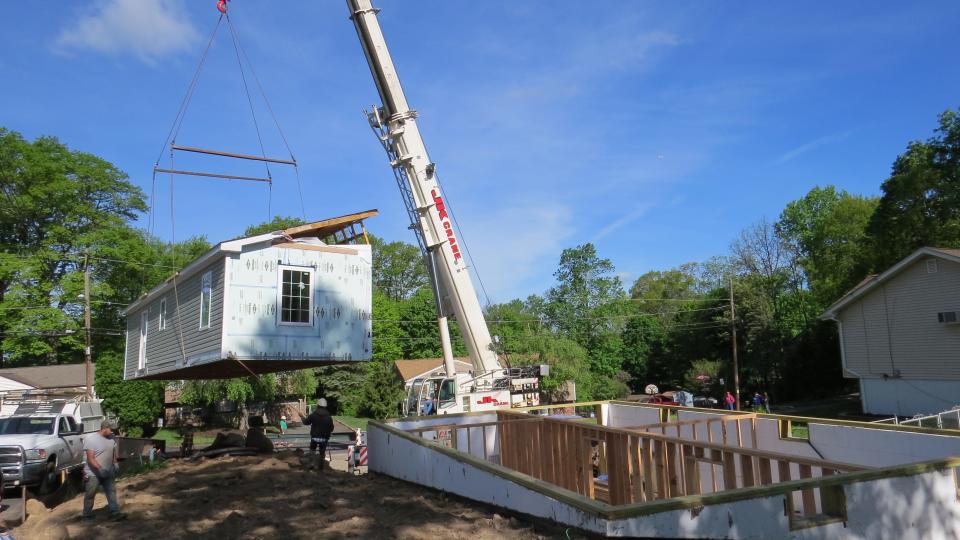 Hoisted by crane onto a flatbed truck, a  modular Habitat for Humanity home built by students at Roxbury High School was moved across town to a permanent location in Landing as the couple selected to own it watches.