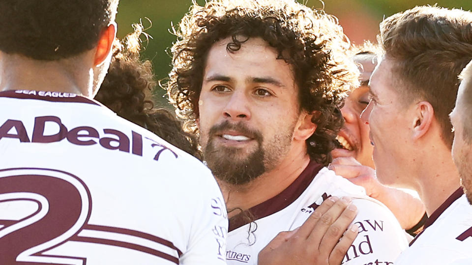 Josh Aloiai is pictured being crowded by Manly Sea Eagles teammates.