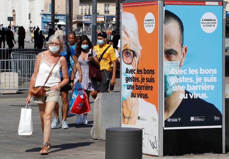 FILE PHOTO: People wearing protective face masks walk near the Old Port in Marseille