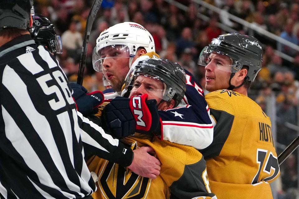 Mar 23, 2024; Las Vegas, Nevada, USA; Columbus Blue Jackets center Brendan Gaunce (16) grabs ahold of Vegas Golden Knights right wing Jonathan Marchessault (81) as Vegas Golden Knights defenseman Ben Hutton (17) joins the play during the first period at T-Mobile Arena. Mandatory Credit: Stephen R. Sylvanie-USA TODAY Sports