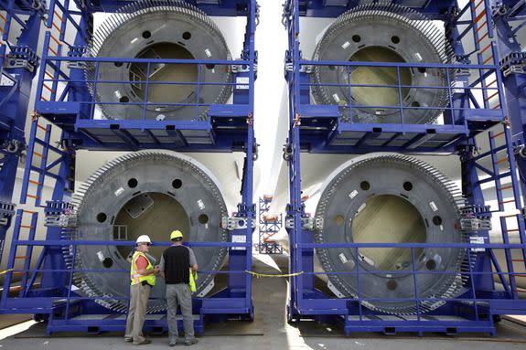 Workers stand near over-sized racks holding sections of Deepwater Wind's wind turbine towers at a staging site in Providence, R.I., July 2016.