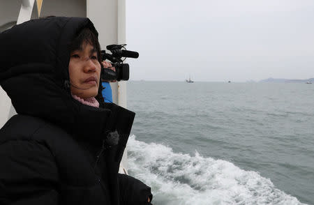 A relative of a victim watches a salvage operation of sunken ferry Sewol at the sea off Jindo, South Korea, March 22, 2017. Yonhap via REUTERS