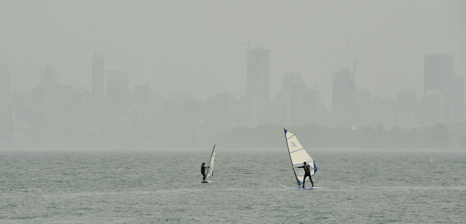 People windsurf in Burrard inlet as the heavy smog and smell of wood smoke hangs over the Vancouver, British Columbia skyline in the background on September, 16, 2020. - Smoke from California and Oregon wildfires has cloaked Vancouver, known for its majestic mountain views and fresh ocean breezes, in the dirtiest air in the world this week. Days have been spent smarting under a thick haze that has irritated eyes and throats, and sent asthmatics gasping for breath. It has also complicated Covid-19 testing. On September 18, 2020, despite forecasted smoke-clearing rain storms, the city, 800 miles (1,300 km) north of the biggest California fires, topped for the second time this week the World Air Quality Index for worst air quality, after briefly ceding first place to fire-stricken Portland, Oregon. (Photo by Don MacKinnon / AFP) (Photo by DON MACKINNON/AFP via Getty Images)