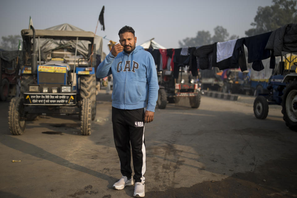 Hardeep Singh, 42, stands for a photograph next to his tractor trailer parked on a highway as he joins tens of thousands of protesting farmers for a protest against new farm laws at the Delhi-Haryana state border, India, Tuesday, Dec. 1, 2020. The protests started in September but drew nationwide attention last week when the farmers marched from northern Punjab and Haryana, two of India's largest agricultural states. Their rallying call is “Inquilab Zindabad” (“Long live the revolution”). (AP Photo/Altaf Qadri)