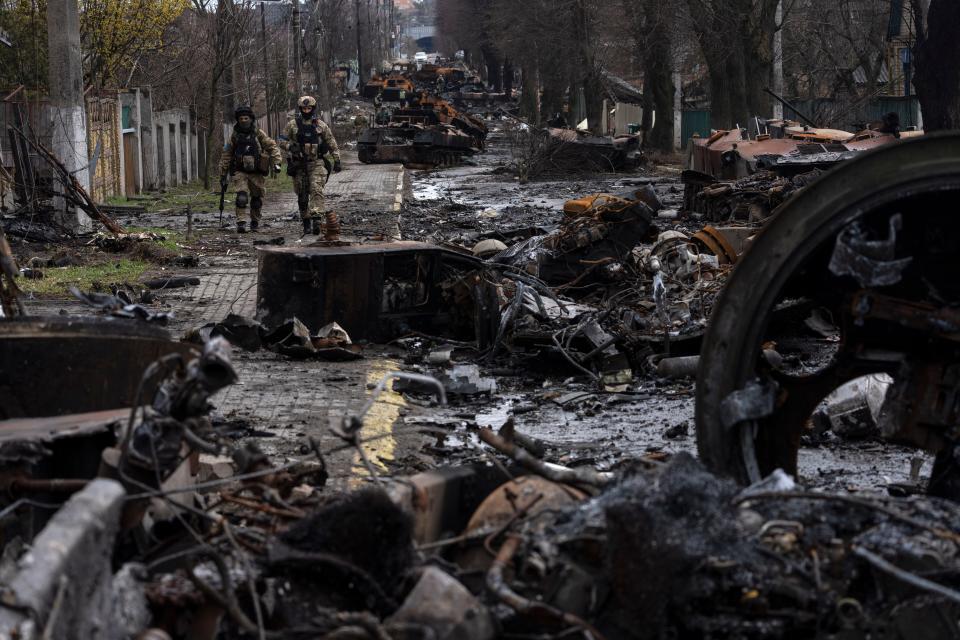 Soldiers walk amid destroyed Russian tanks in Bucha.