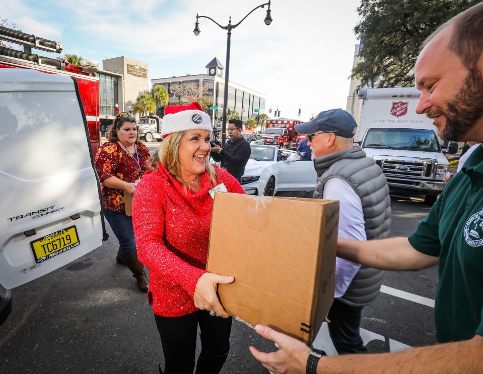 Karla Greenway, CEO of Interfaith Emergency Services, hands off a box of food to Greg Harrell, clerk of courts for Marion County, as residents of Marion County dropped off canned and dried food goods for the annual Bring the Harvest Home food drive Friday morning.