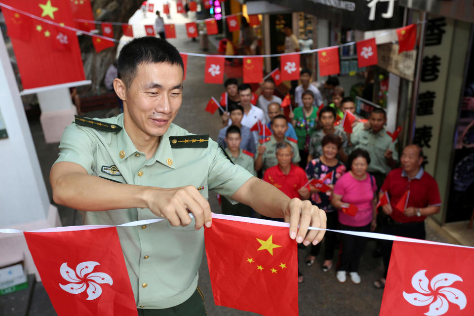 <p>A Chinese paramilitary policeman arranges Chinese and Hong Kong flags during an event marking the 20th anniversary of Hong Kong’s handover from British to Chinese rule, on Chung Ying Street in Shenzhen, at the border with Hong Kong, Guangdong province, China, June 30, 2017. (Photo: Stringer/Reuters) </p>