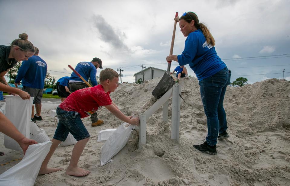 Volunteers Amanda Selway and Camden Chancey, 7, collaborate filling sand bags Tuesday, August 29, 2023, in Pine Island in an effort to help local residents prepare for the potential impact of Hurricane Idalia.  