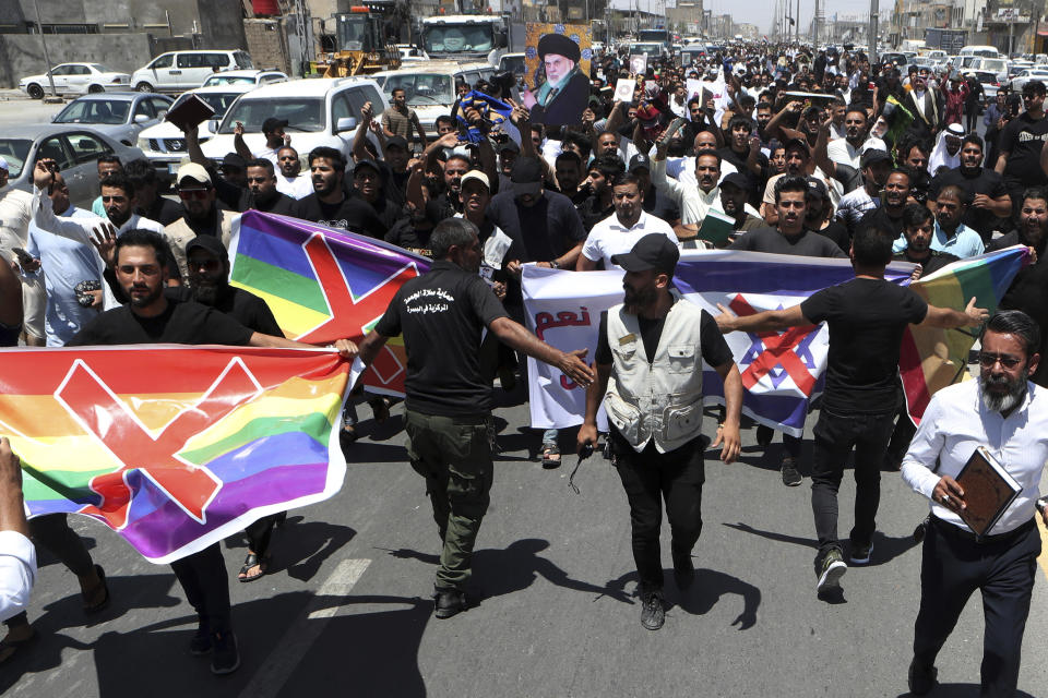 Followers of the Shiite cleric Muqtada al-Sadr carry defaced LGBTQ+ flag during a demonstration, in response to the burning of a copy of the Quran in Sweden, during open-air Friday prayers in Basra, Iraq, Friday, June 30, 2023. (AP Photo/ Nabil al-Jurani)