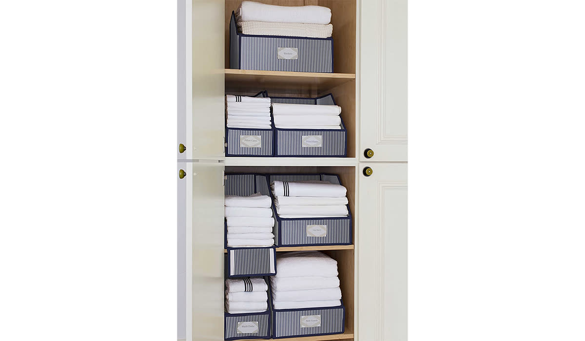 Linen closet full of folded white towels organized in these linen bins of various sizes.