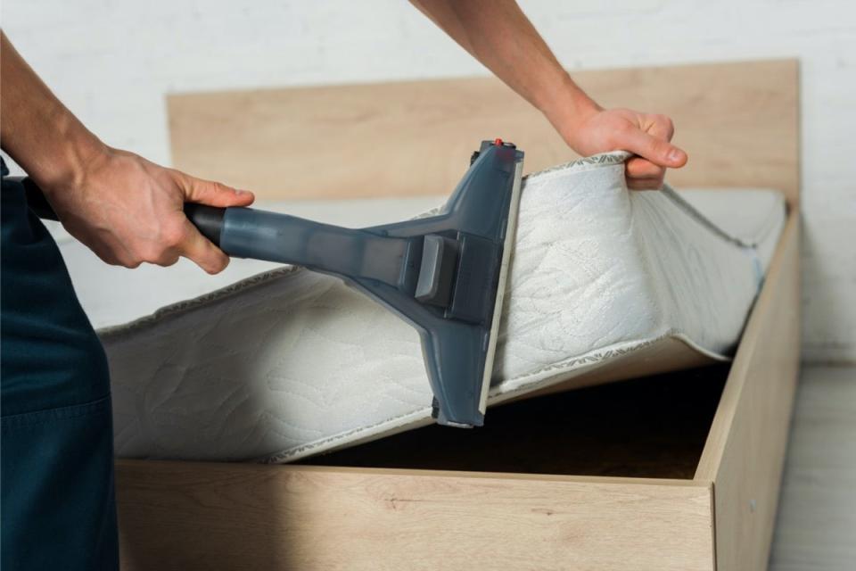 Person using a vacuum attachment to vacuum side of mattress