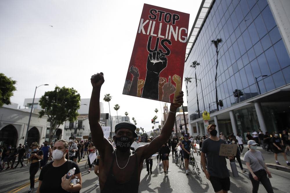 A protester carries a sign in the Hollywood area of Los Angeles on June 1, 2020, during demonstrations after the killing of George Floyd, which sparked calls for a racial reckoning to address structural racism that has created longstanding inequities impacting generations of Black Americans. (AP Photo/Marcio Jose Sanchez, File)