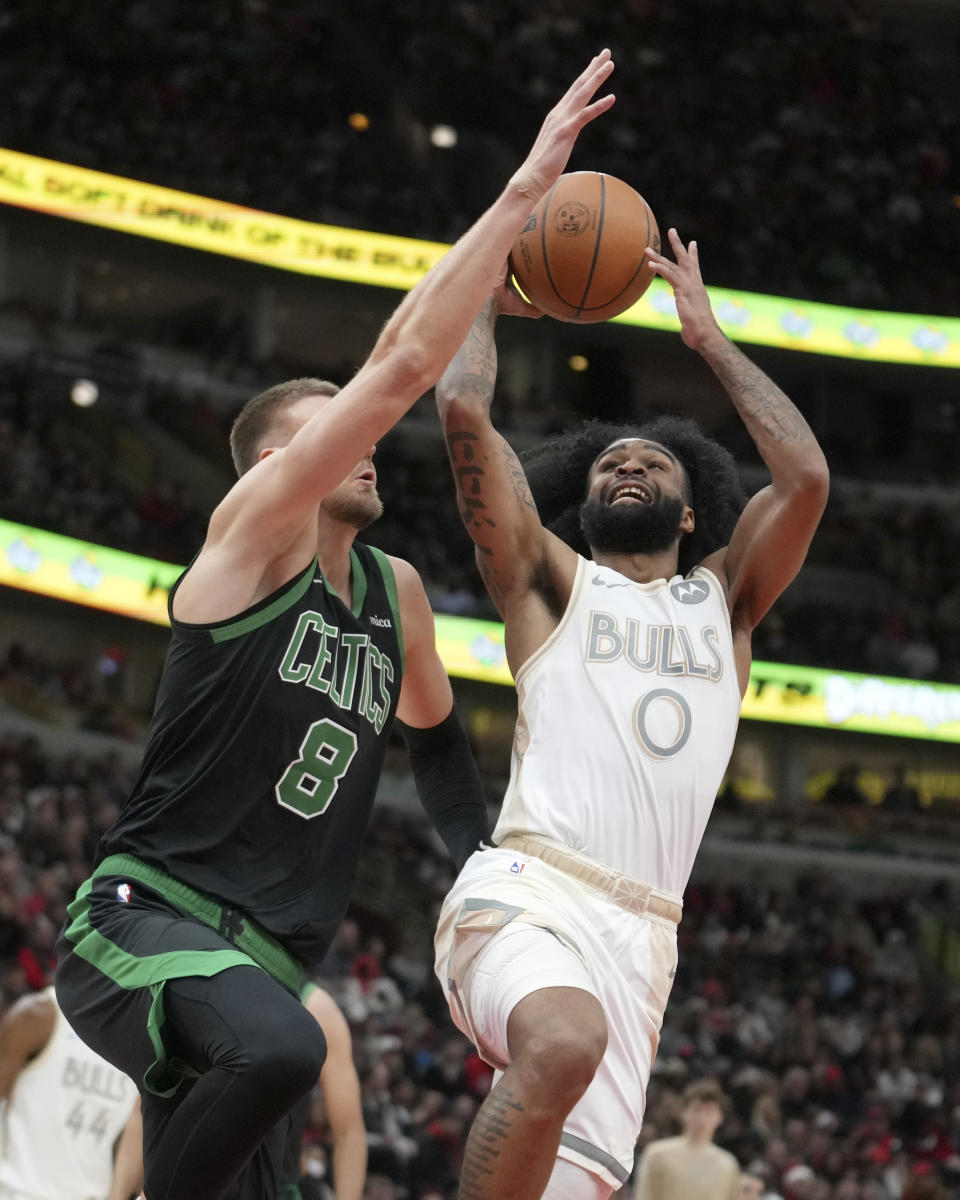 Chicago Bulls' Coby White (0) drives to the basket as Boston Celtics' Kristaps Porzingis defends during the second half of an NBA basketball game Saturday, Dec. 21, 2024, in Chicago. (AP Photo/Charles Rex Arbogast)