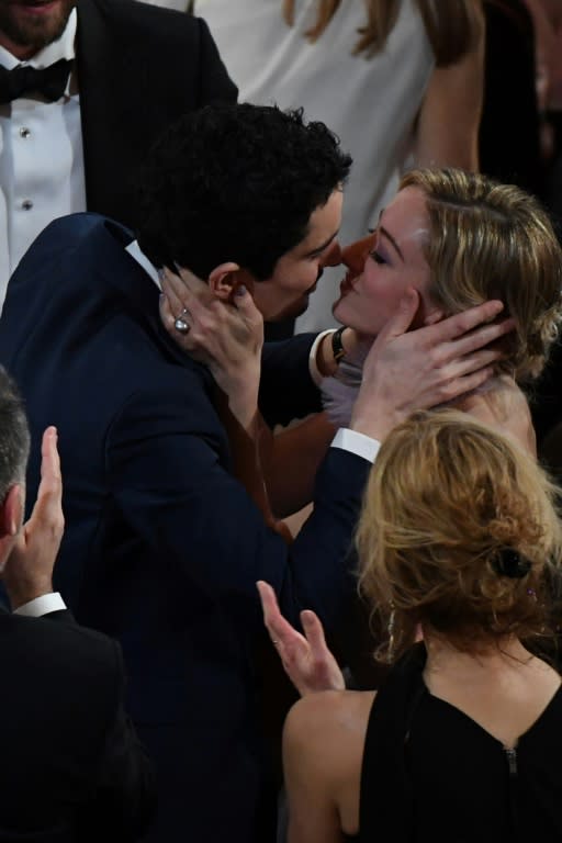 US director Damien Chazelle (L) kisses his partner Olivia Hamilton after he won the best director award for "La La Land" at the Oscars on February 26, 2017