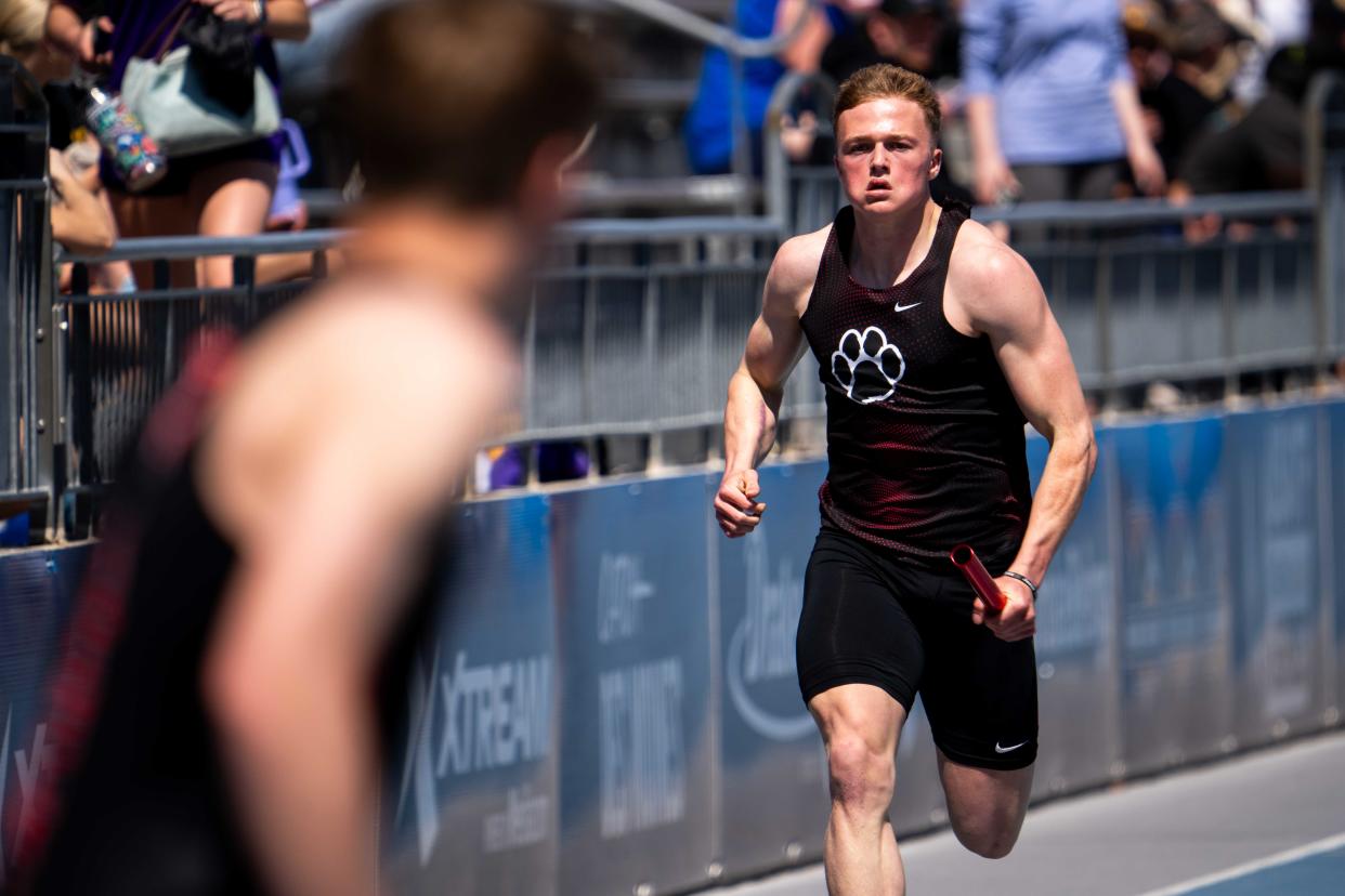 ADM's Brevin Doll races to his teammate to hand off the baton during the boy's distance medley Saturday, April 13, 2024, at Drake Stadium in Des Moines.