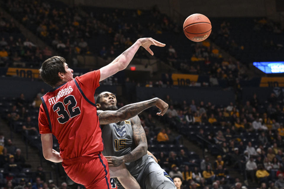 Stony Brook center Keenan Fitzmorris (32) and West Virginia forward Jimmy Bell Jr. (15) vie for the ball during the second half of an NCAA college basketball game Thursday, Dec. 22, 2022, in Morgantown, W.Va. (William Wotring/The Dominion-Post via AP)