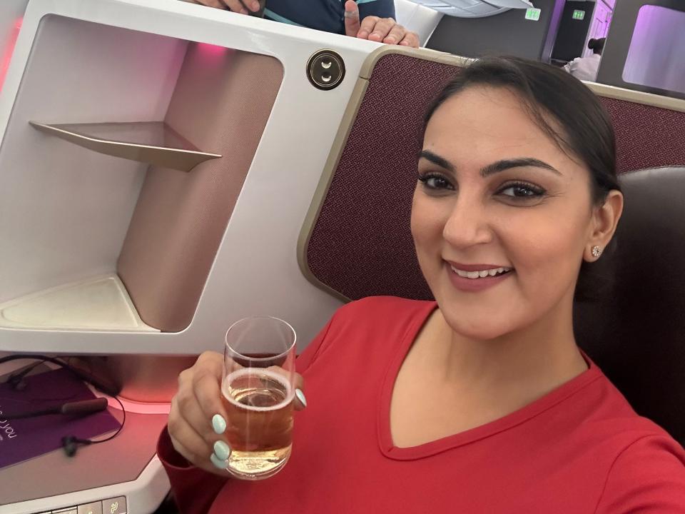 Noor Anand Chawla and her husband holding drinks and smiling in business-class.