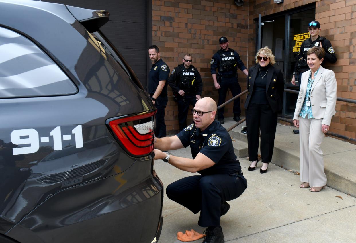 Massillon Police Chief Jason Saintenoy slaps a "City of Champions" decal onto the back of one of the department's new Dodge Durango SUVs.