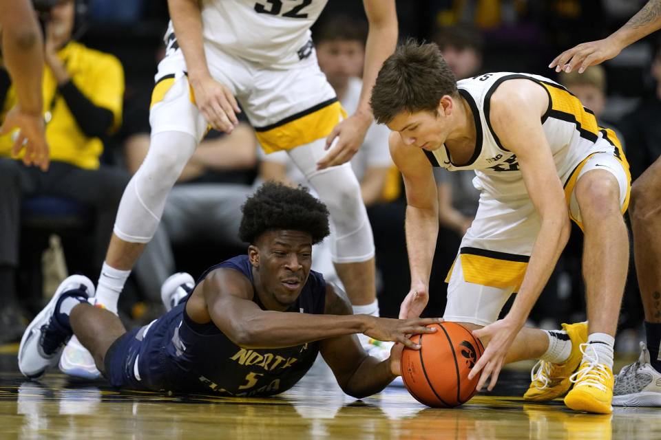 North Florida guard Dorian James, left, fights for a loose ball with Iowa forward Pryce Sandfort during the second half of an NCAA college basketball game, Wednesday, Nov. 29, 2023, in Iowa City, Iowa. Iowa won 103-78. (AP Photo/Charlie Neibergall)
