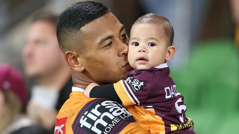 Jamayne Isaako is seen here holding his child after a Brisbane Broncos match.