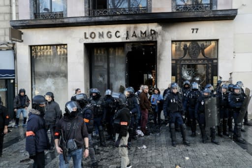 Riot police outside a partially burned Longchamps store on the Champs-Elysees in Paris on Saturday
