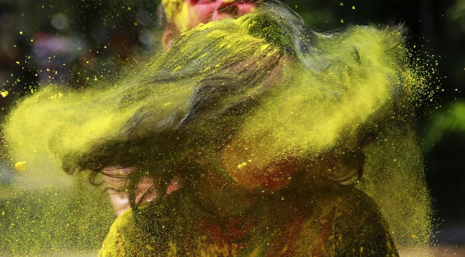 An Indian woman shakes her head covered in colored powder as she celebrates Holi, the Hindu festival of colors, in Mumbai India, Monday, March 17, 2014. The festival heralds the arrival of spring. (AP Photo/ Rafiq Maqbool)