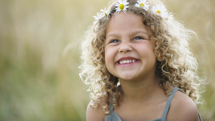 young girl laughing with daisies in hair