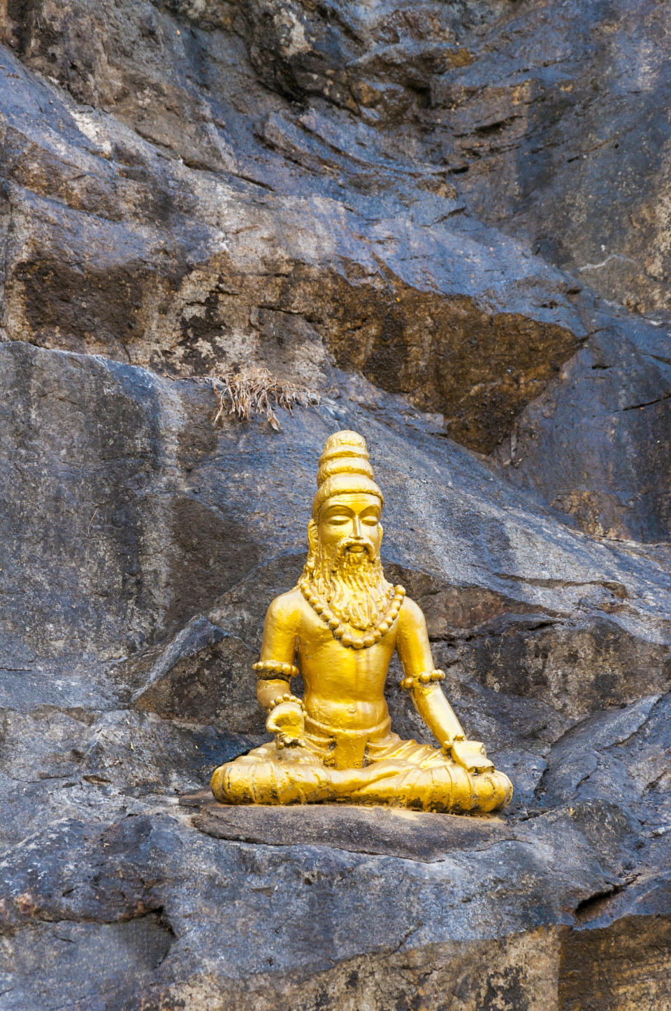 Murudeshwar, Karnataka, India - January 6, 2015:  Golden sculpture of Vyasa the sage sitting and meditating on the rock in Murudeshwar Temple complex.