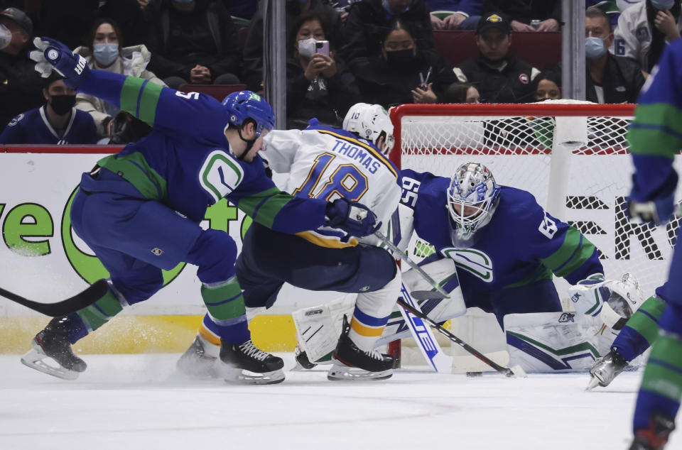 St. Louis Blues' Robert Thomas (18) is stopped by Vancouver Canucks goalie Michael DiPietro (65) as Tucker Poolman (5) defends during the second period of an NHL hockey game in Vancouver, British Columbia, Sunday, Jan. 23, 2022. (Darryl Dyck/The Canadian Press via AP)