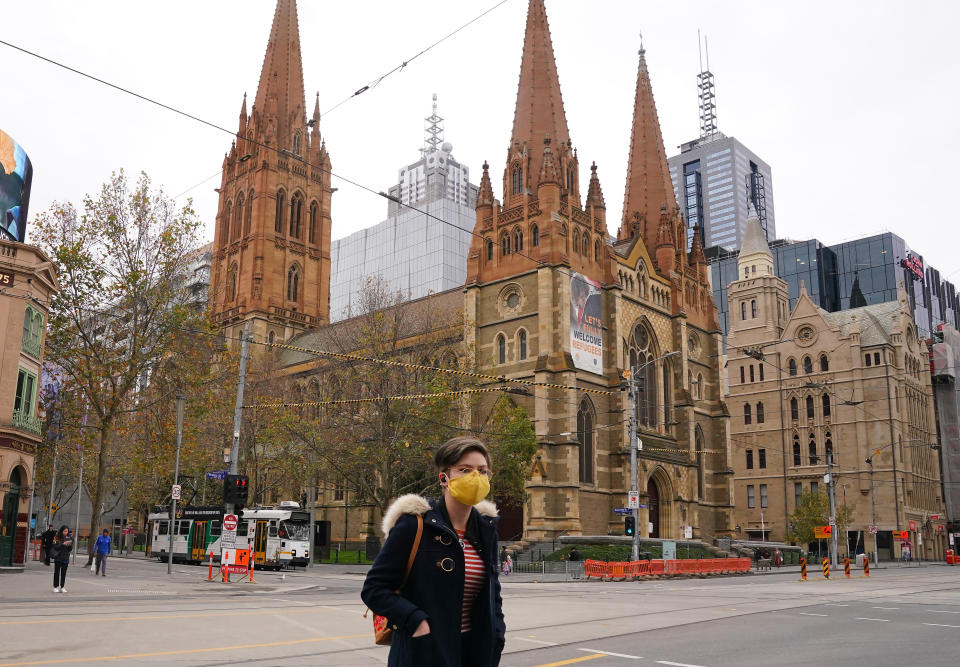 A woman walks past St Paul's Cathedral while wearing a face mask as a preventive measure against the spread of novel coronavirus COVID-19 in Melbourne, Sunday, June 21, 2020. 