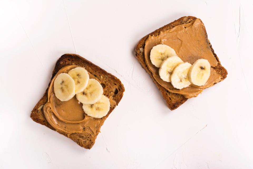 whole grain toast with peanut butter and banana slices on white background