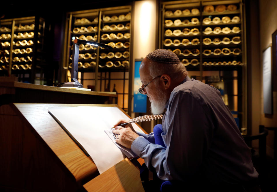 With ancient scrolls as a backdrop, Israeli Eliezer Adam works with ink and feather copying the Five Books of Moses, which he says will take a year, at the Museum of the Bible in Washington&nbsp;on Nov. 14. (Photo: Kevin Lamarque/Reuters)