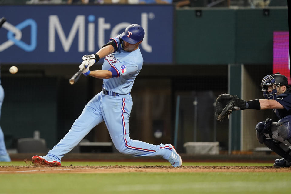 Texas Rangers' Corey Seager, left, hits a double in front of Seattle Mariners catcher Curt Casali during the seventh inning of a baseball game in Arlington, Texas, Sunday, Aug. 14, 2022. The Rangers won 5-3. (AP Photo/LM Otero)